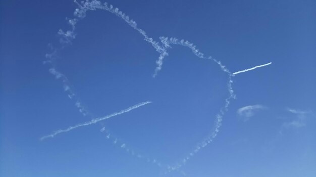 Low angle view of heart made of vapor trail