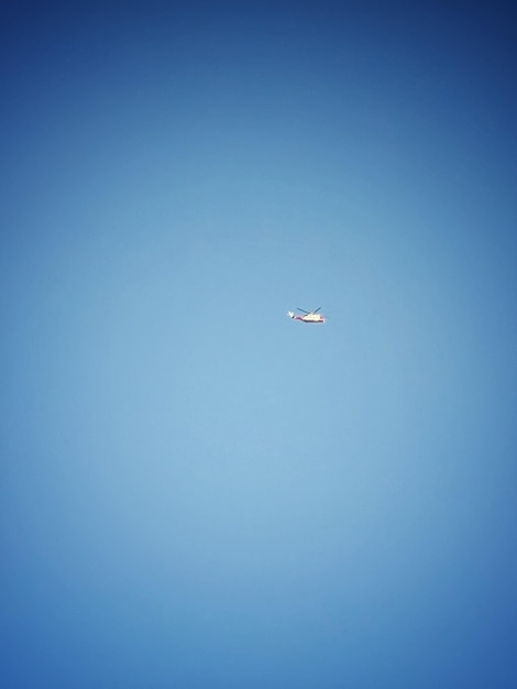 Low angle view of helicopter flying against clear blue sky