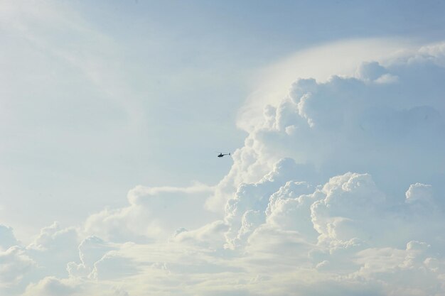 Low angle view of helicopter flying in cloudy sky