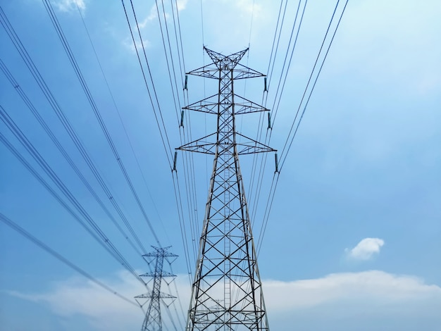 Low Angle View of High Voltage Tower and Power Lines Against Blue Cloudy Sky