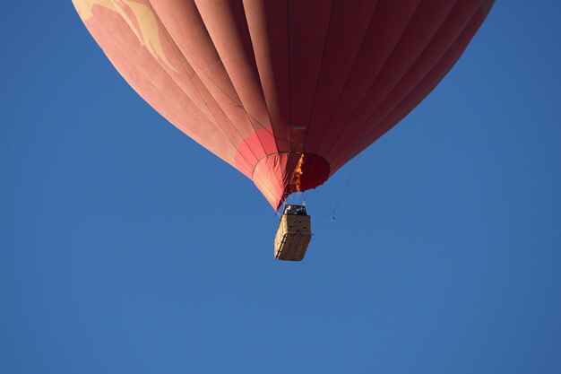 Foto vista a basso angolo di un palloncino ad aria calda contro un cielo blu limpido.