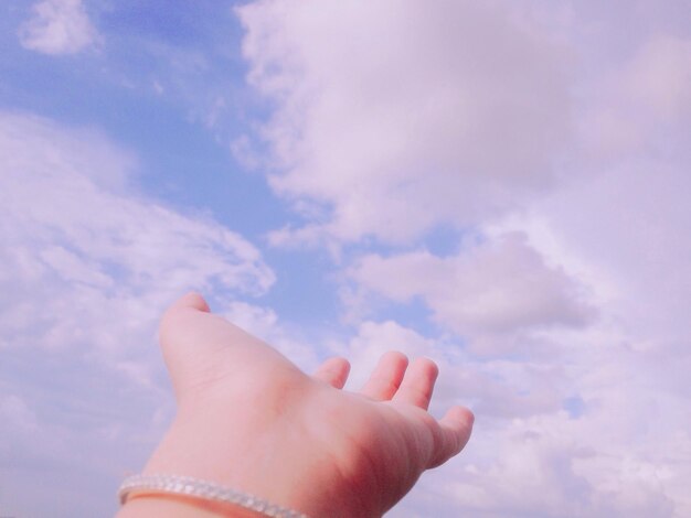 Low angle view of human hand against sky