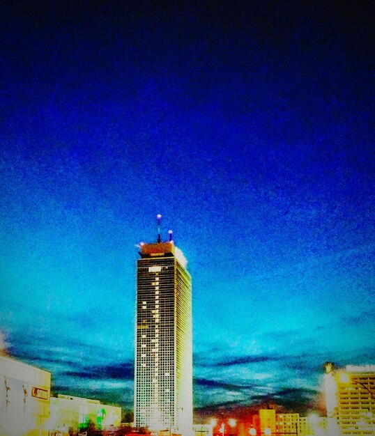 Low angle view of illuminated buildings against blue sky