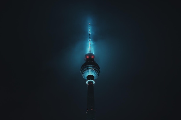 Low angle view of illuminated communications tower against sky at night