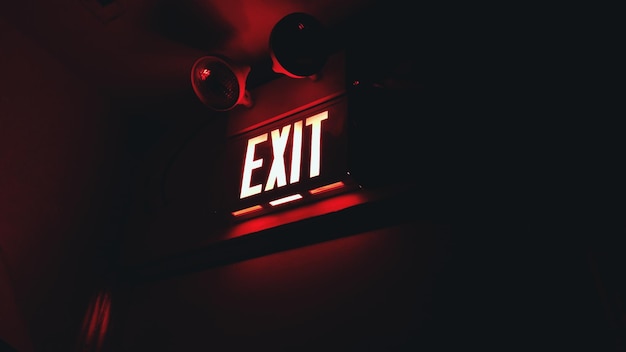 Photo low angle view of illuminated exit sign on wall in dark