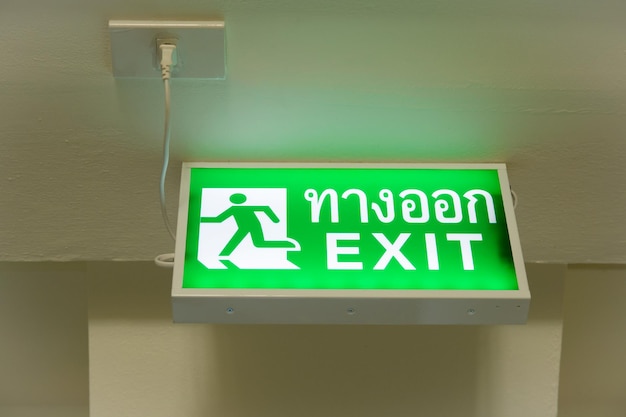 Photo low angle view of illuminated exit sign with text on wall