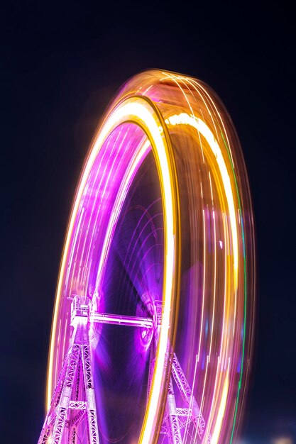 Low angle view of illuminated ferris wheel spinning against sky at night