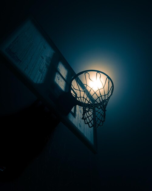 Photo low angle view of illuminated lamp against blue sky and basketball hoop