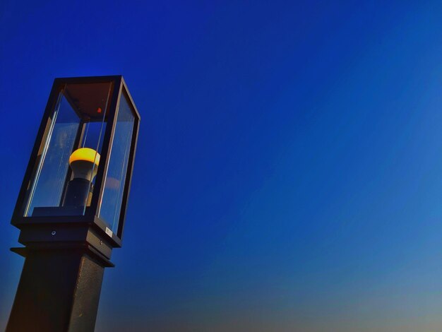 Low angle view of illuminated lamp against blue sky