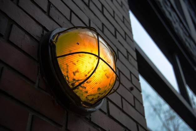 Low angle view of illuminated lamp against wall