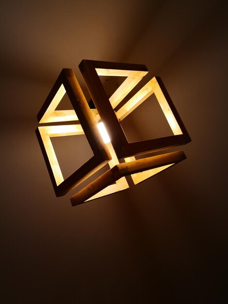 Low angle view of illuminated lamp against wall