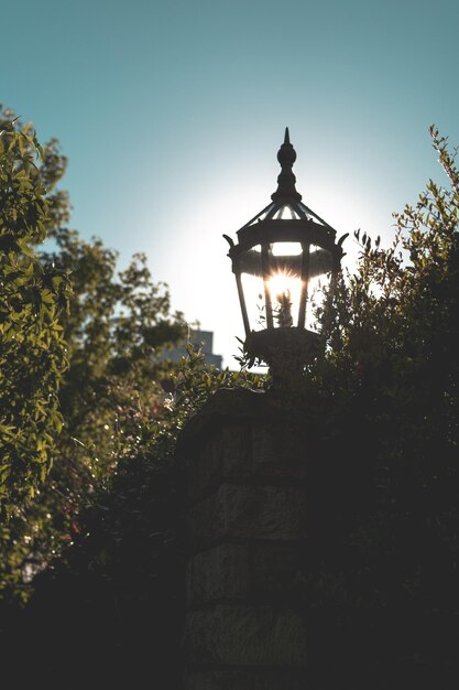 Low angle view of illuminated lamp by building against sky