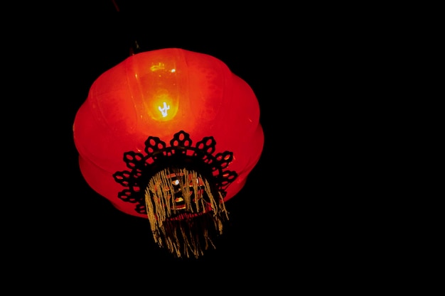 Foto vista a basso angolo di una lanterna illuminata appesa su uno sfondo nero
