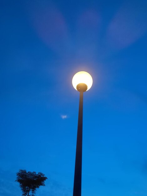 Low angle view of illuminated light against blue sky