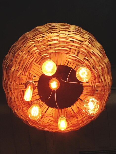 Low angle view of illuminated light bulb against black background