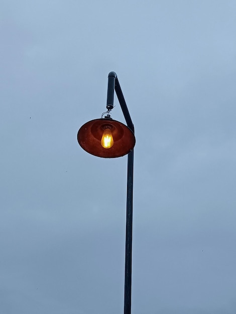 Low angle view of illuminated light bulb against sky