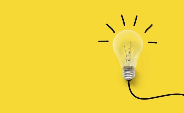 Low angle view of illuminated light bulb against yellow wall