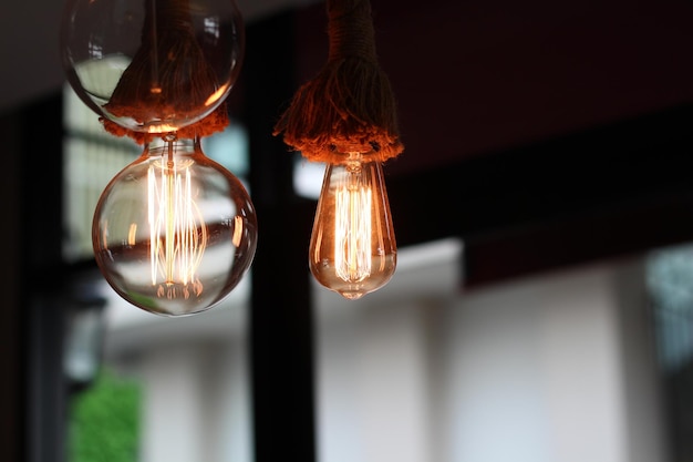 Low angle view of illuminated light bulb hanging from ceiling