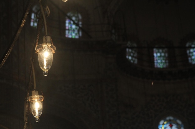 Low angle view of illuminated light bulb hanging from ceiling