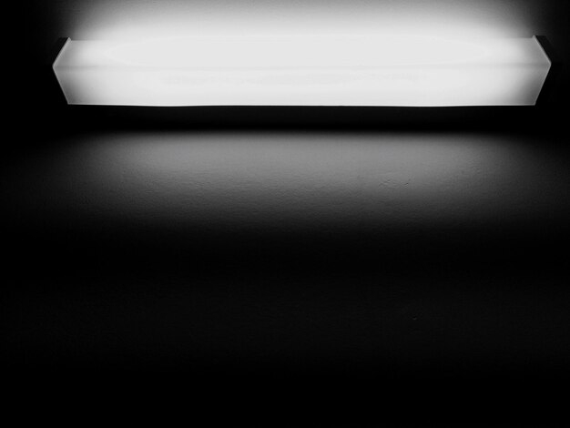 Low angle view of illuminated light bulb on wall in darkroom