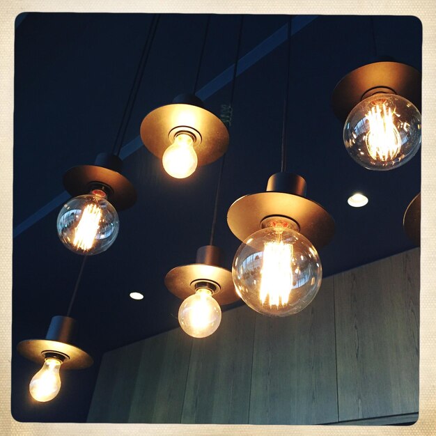 Low angle view of illuminated light bulbs hanging on ceiling