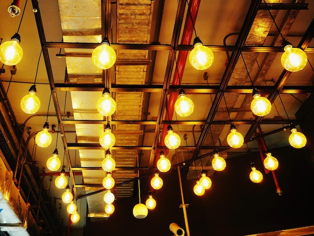 Low angle view of illuminated light bulbs hanging from ceiling