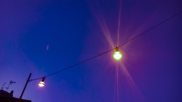 Low angle view of illuminated lights against sky at sunset