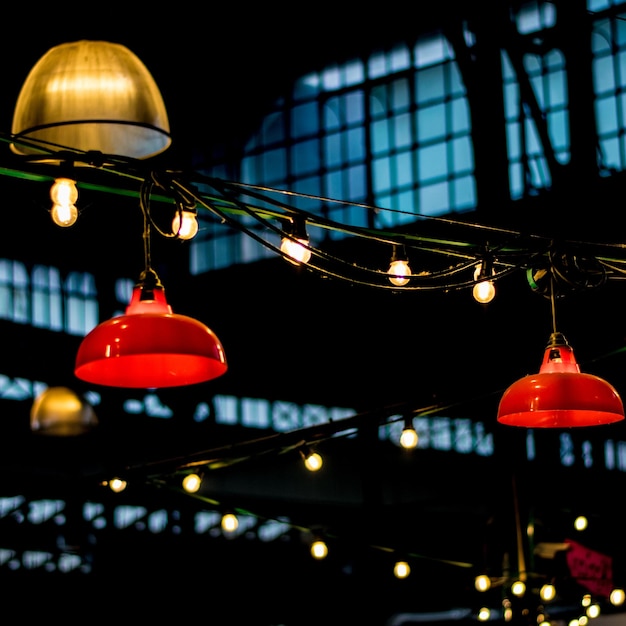 Photo low angle view of illuminated lights hanging against buildings