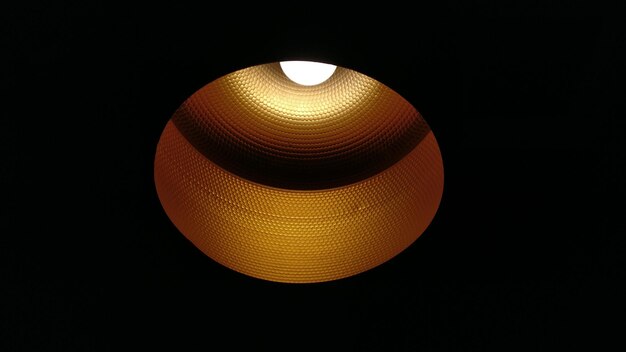 Photo low angle view of illuminated pendant light against black background