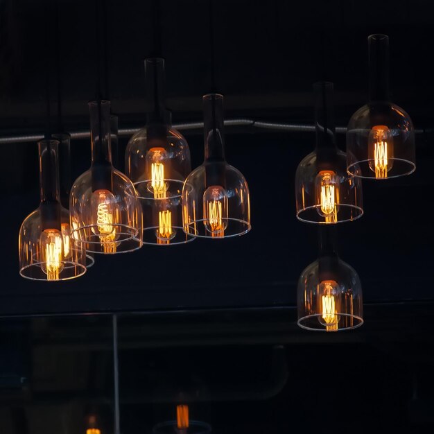 Photo low angle view of illuminated pendant lights hanging in darkroom