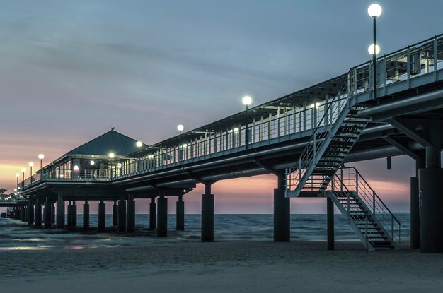 Foto vista a basso angolo del molo illuminato sopra il mare al tramonto