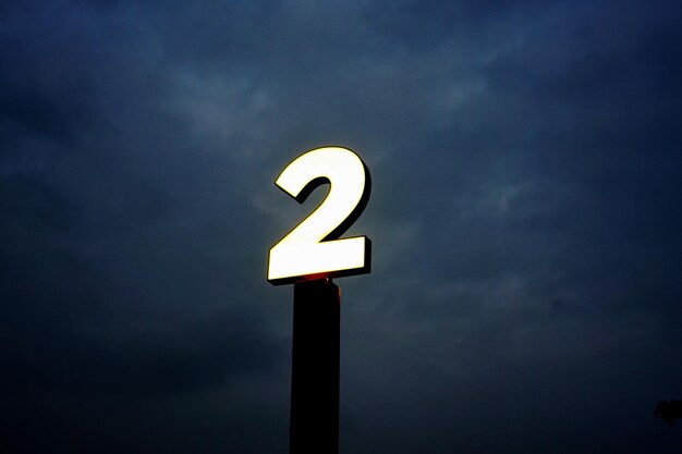 Photo low angle view of illuminated sign against sky at night