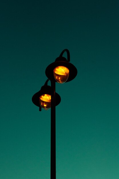 Low angle view of illuminated street light against blue sky