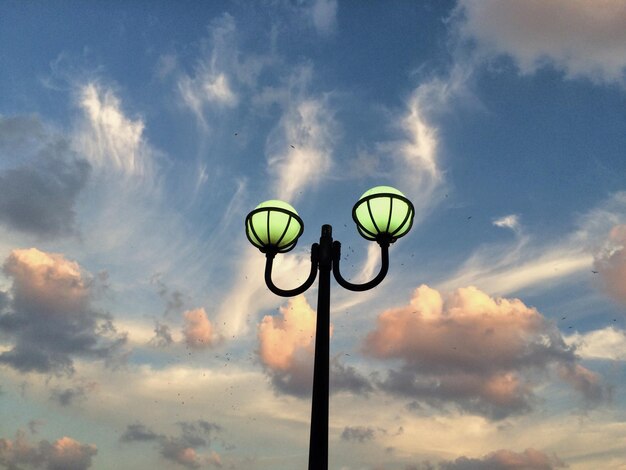 夕暮れの雲の空に照らされたストリートライトの低角度のビュー