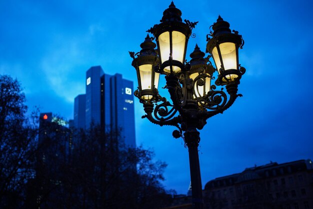 Low angle view of illuminated street light and building against cloudy sky at dusk