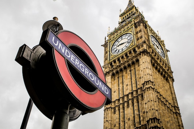 Low angle view of information sign by big ben against sky