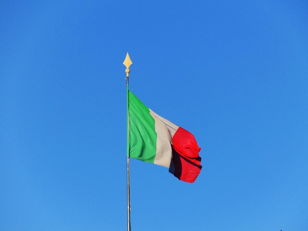 Foto vista a bassa angolazione della bandiera italiana contro un cielo blu limpido