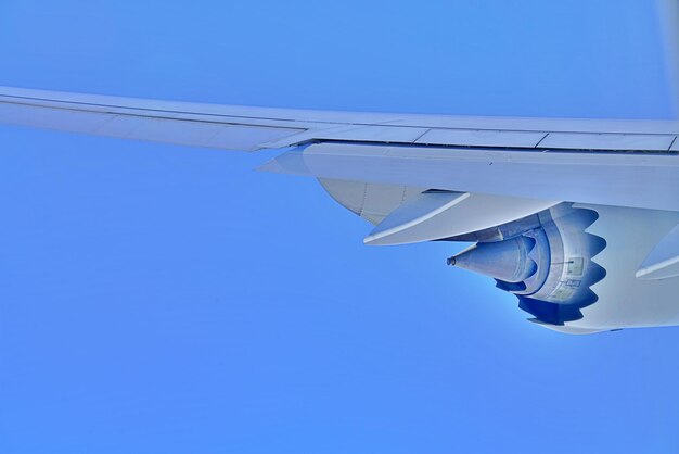 Low angle view of jet engine airplane flying against clear blue sky