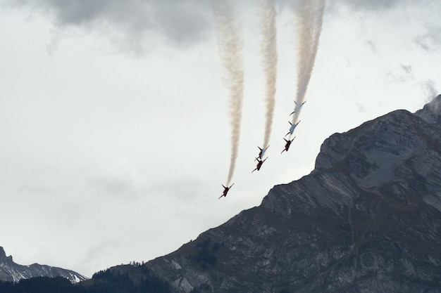 Low angle view of jet planes emitting vapor trail over mountains in sky