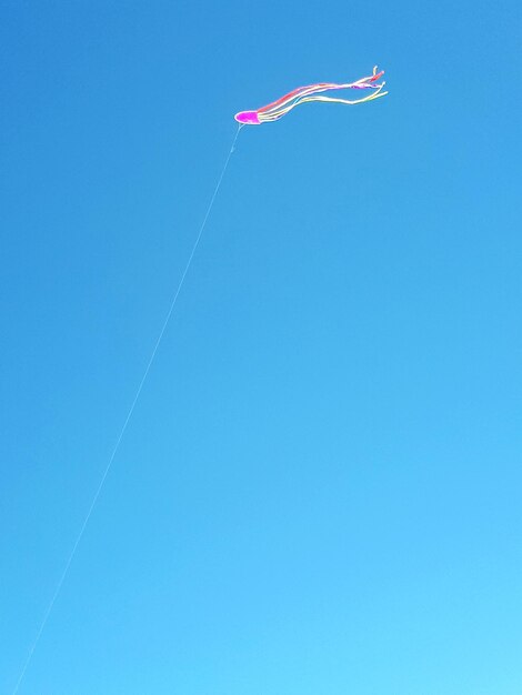 Low angle view of kite against clear blue sky