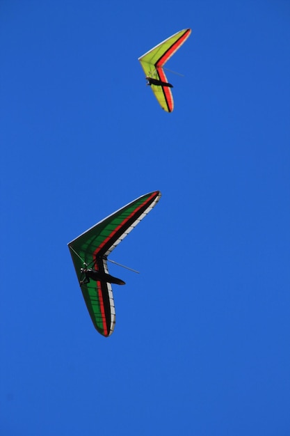 Low angle view of kites flying against clear blue sky