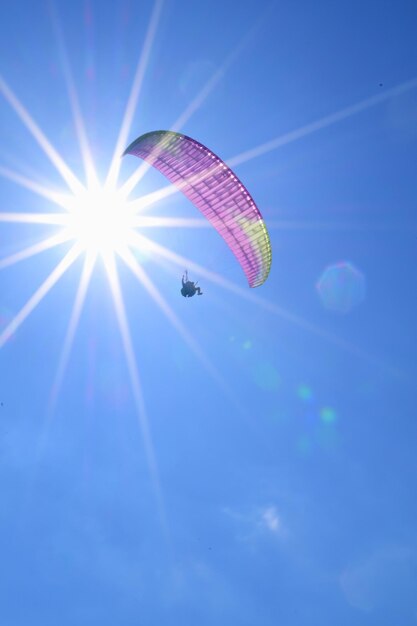 Low angle view of kites flying against sky on sunny day