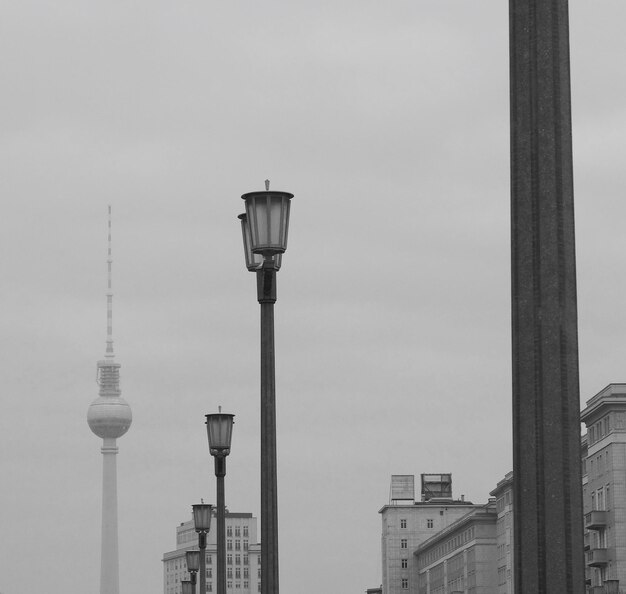 Photo low angle view of lamp posts and fernsehturm against sky in city