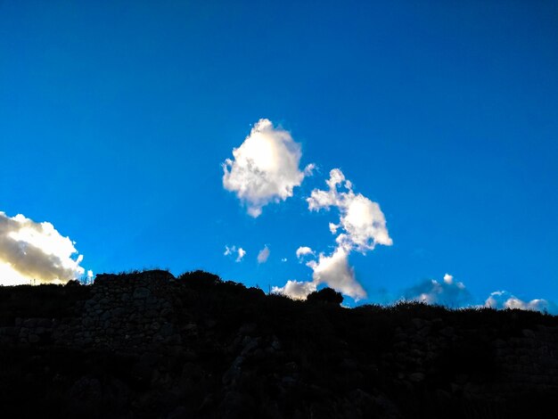 Low angle view of landscape against blue sky