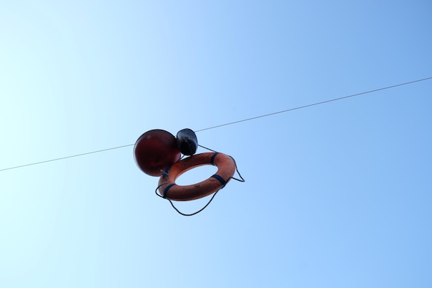 Photo low angle view of life belt hanging against clear blue sky