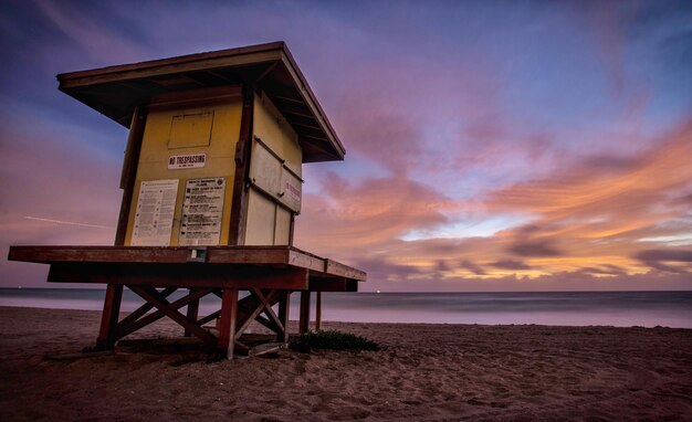 Photo low angle view of lifeguard hut at beach against sky during sunrise