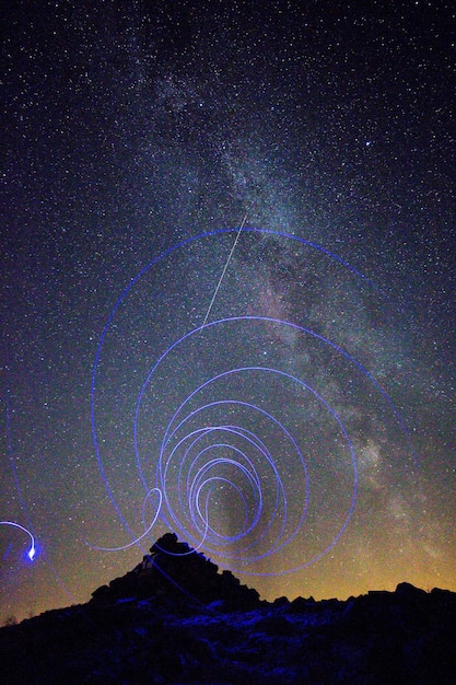 Низкоугольный вид световой живописи на фоне звездного поля ночью