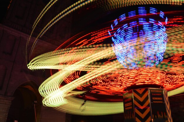Low angle view of light trails on amusement park ride at night