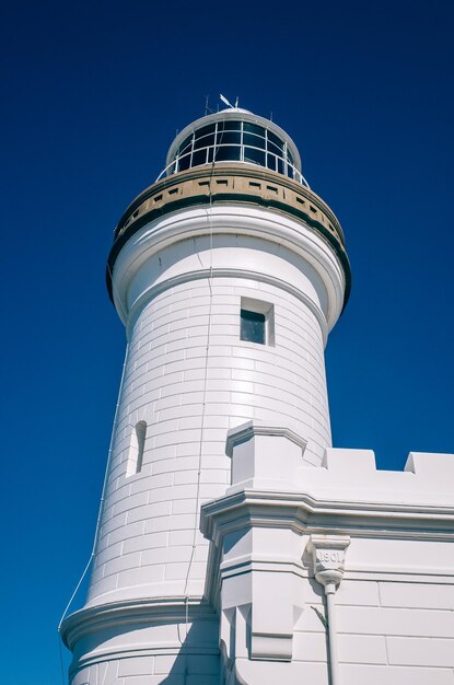 Low angle view of lighthouse against building against clear blue sky