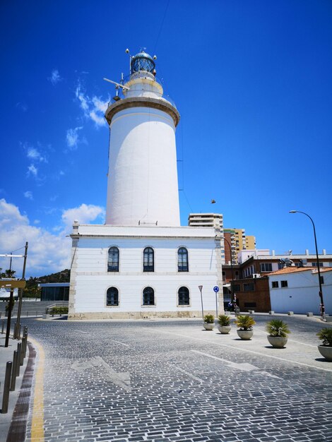 Low angle view of lighthouse by building against sky